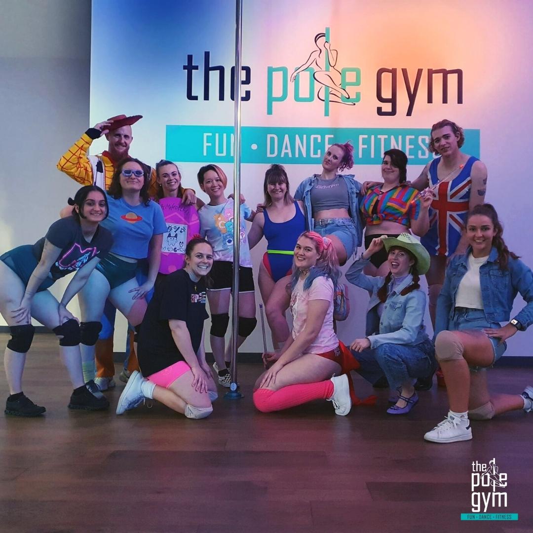 90's themed beginner pole party with friends in fun costumes, having a great time together.